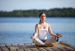 young girl training yoga near a lake